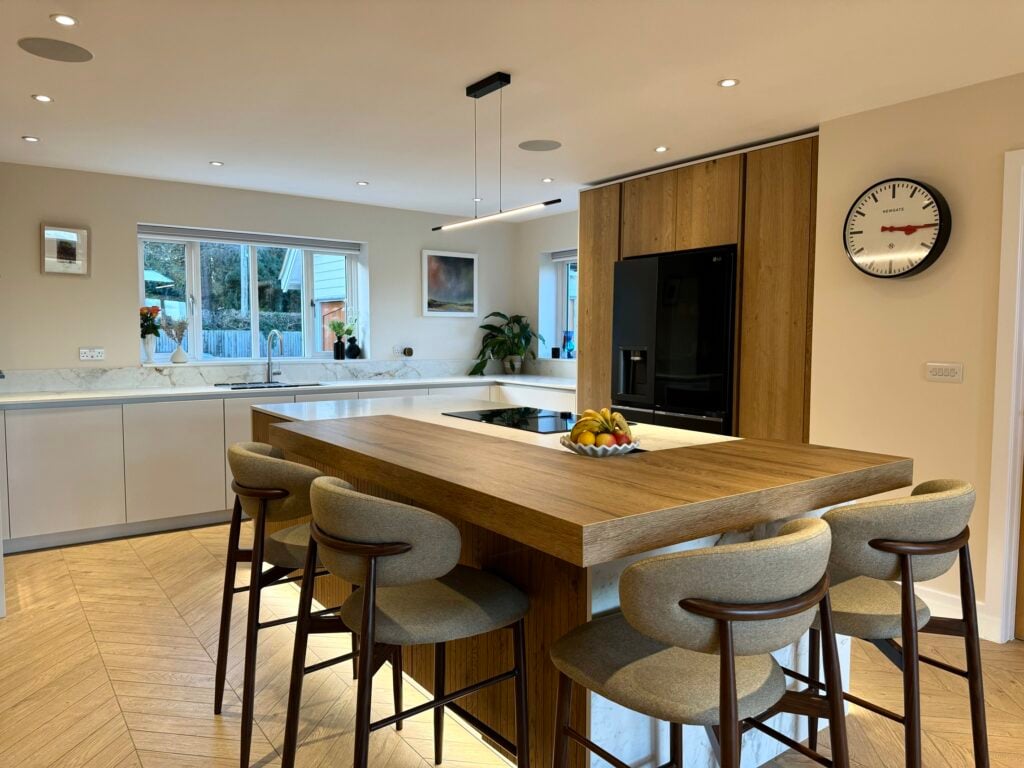 Open-plan handleless kitchen with fluted oak cabinetry, kitchen island seating and integrated appliances