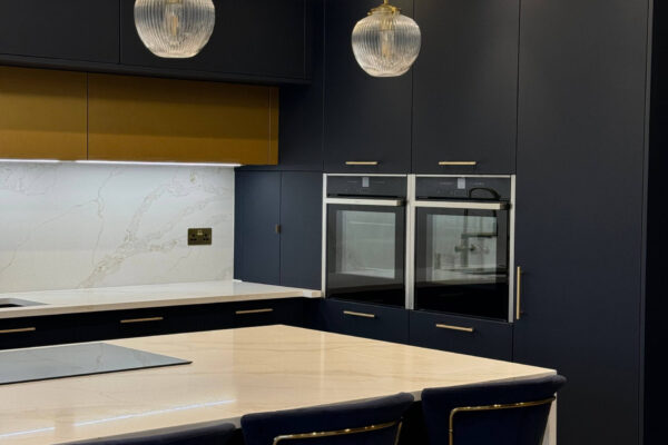 Waterfall kitchen island with quartz worktops and integrated NEFF appliances in a navy blue kitchen